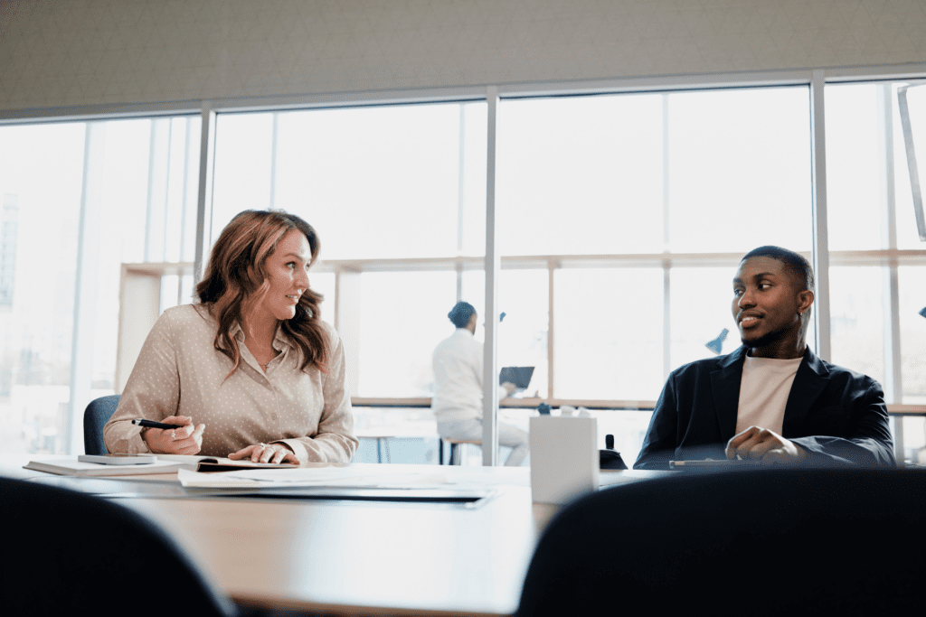 Two colleagues chat in a conference room.