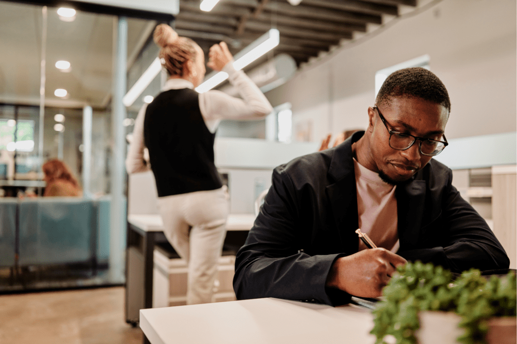 One employee in focus working at his desk among his coworkers