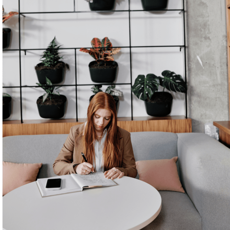 Young professional writes notes in a work setting.